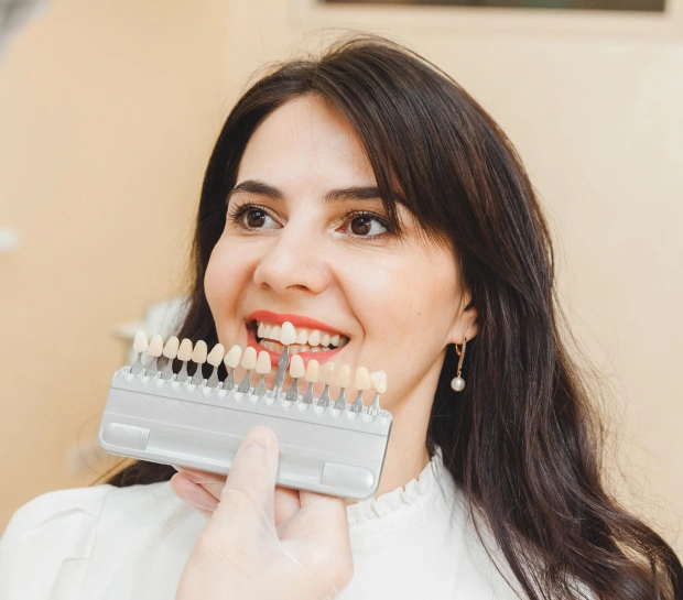 Patient comparing tooth shades for dental veneers treatment in Bedford, TX cosmetic dental office