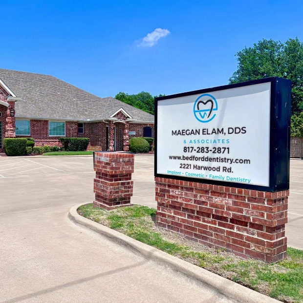 Exterior view of Maegan Elam, DDS & Associates dental office in Bedford, TX with signage showing contact information and services